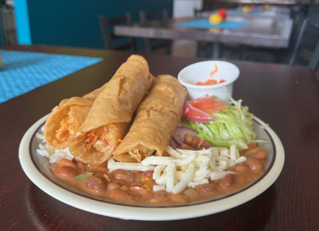 Three chicken flautas on beans with white rice and a small salad at El Paraiso restaurant in Urbana, Illinois.
