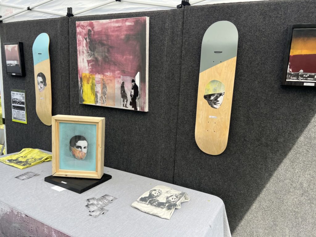 mixed media art on skateboards, canvas, and in glass. Most feature images of a man's face that is partially obscured. 