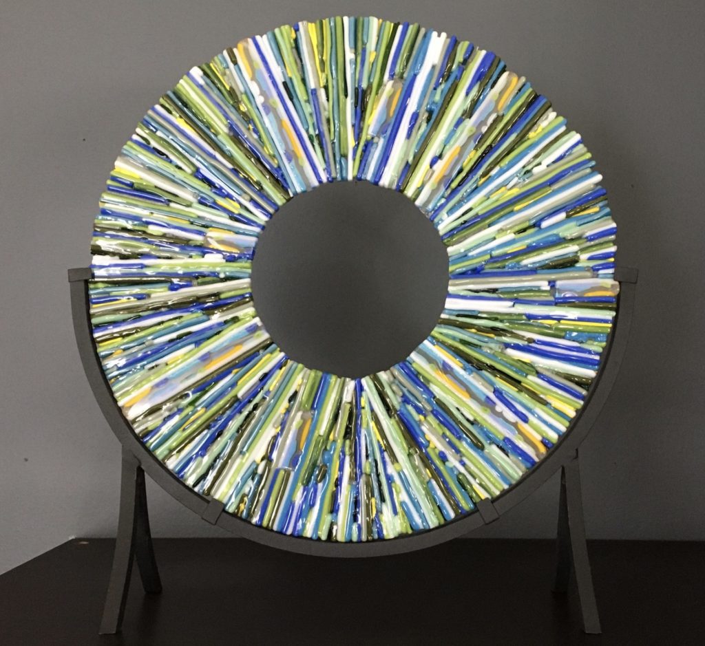 small glass pieces in green, yellow, and blue fused to create a wreath