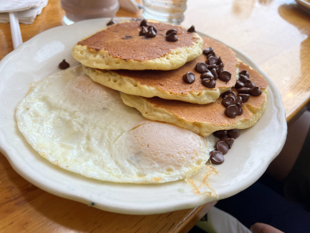 A junior plate of fried eggs and chocolate chip pancakes.