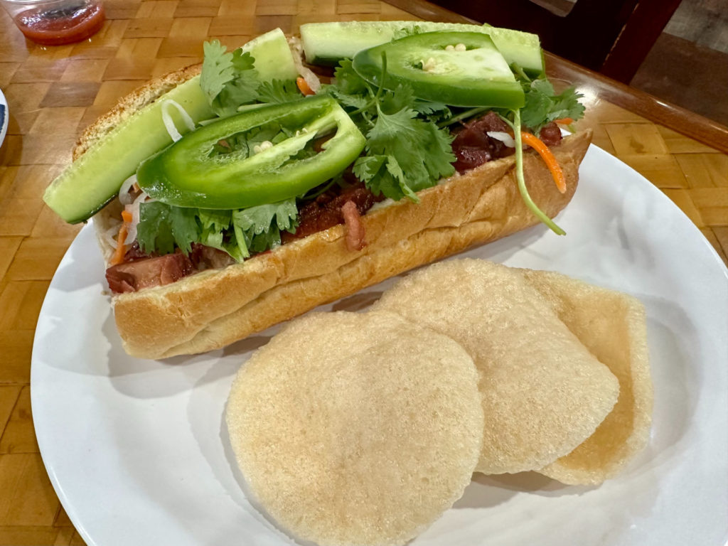 A banh mi sandwich on a white plate at 83 Vietnamese.