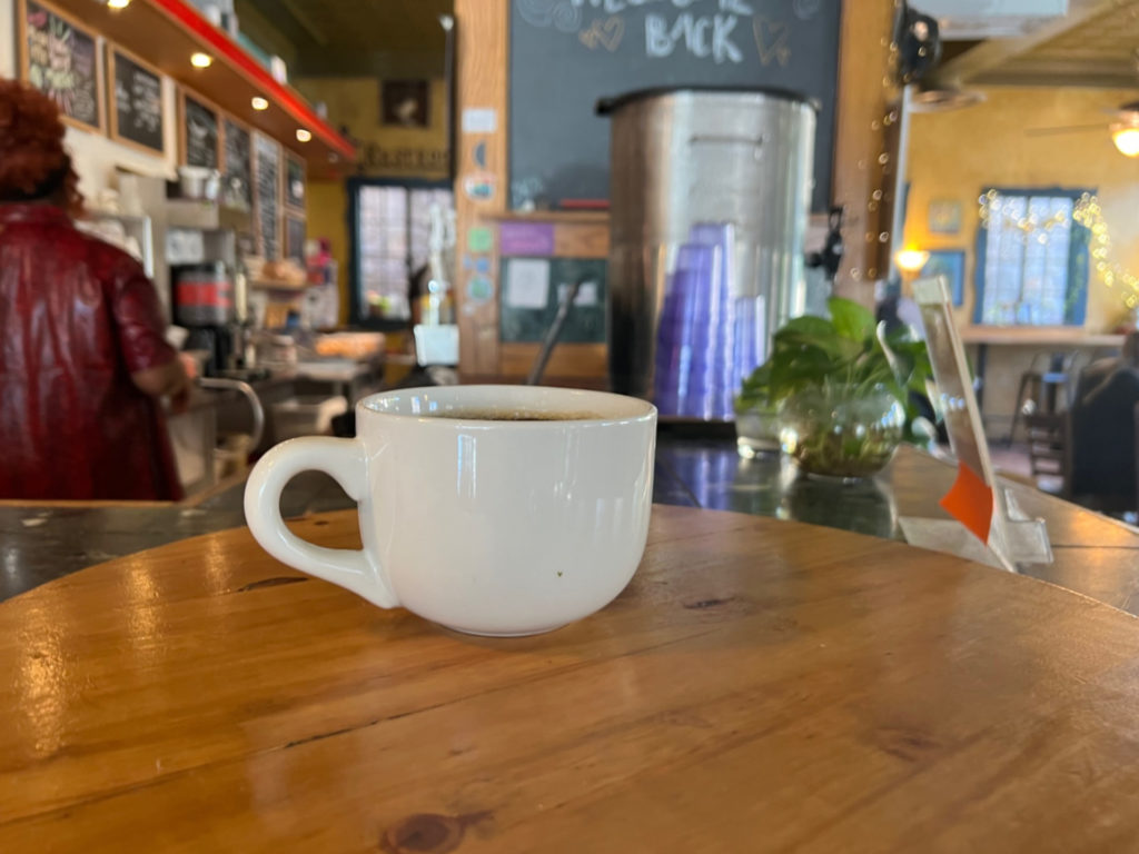 A black coffee in a white mug is on the round pick-up counter inside Caffe Paradiso.