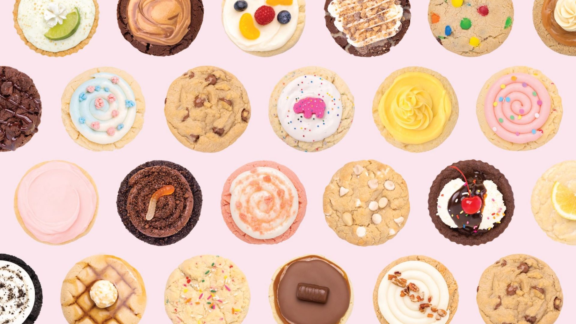 An array of different types of cookies, shot from above on a pink background.