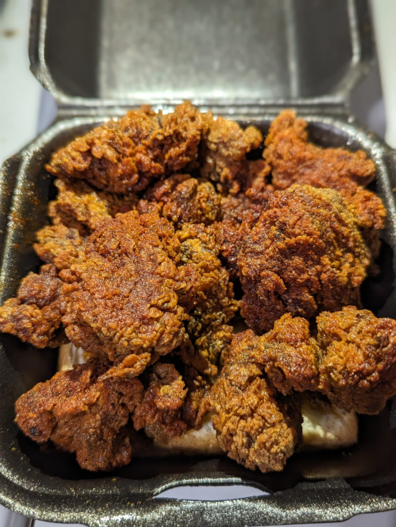 A black styrofoam container of hot chicken from Dave's Hot Chicken.