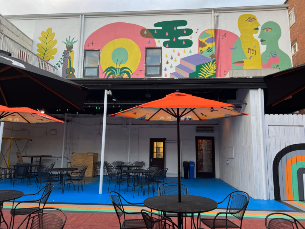 The back patio of Gallery Art Bar has a mural and bright blue concrete floors.