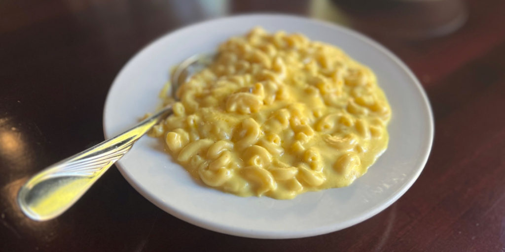 A plate of Hamilton Walker's macaroni and cheese on a dark wooden table.