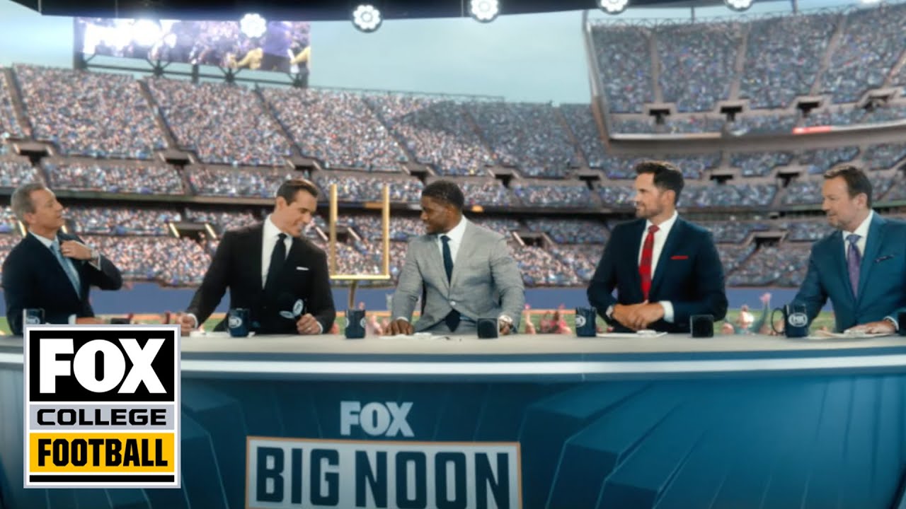 Five commentators in suit jackets sit behind a desk, with a football stadium in the background.