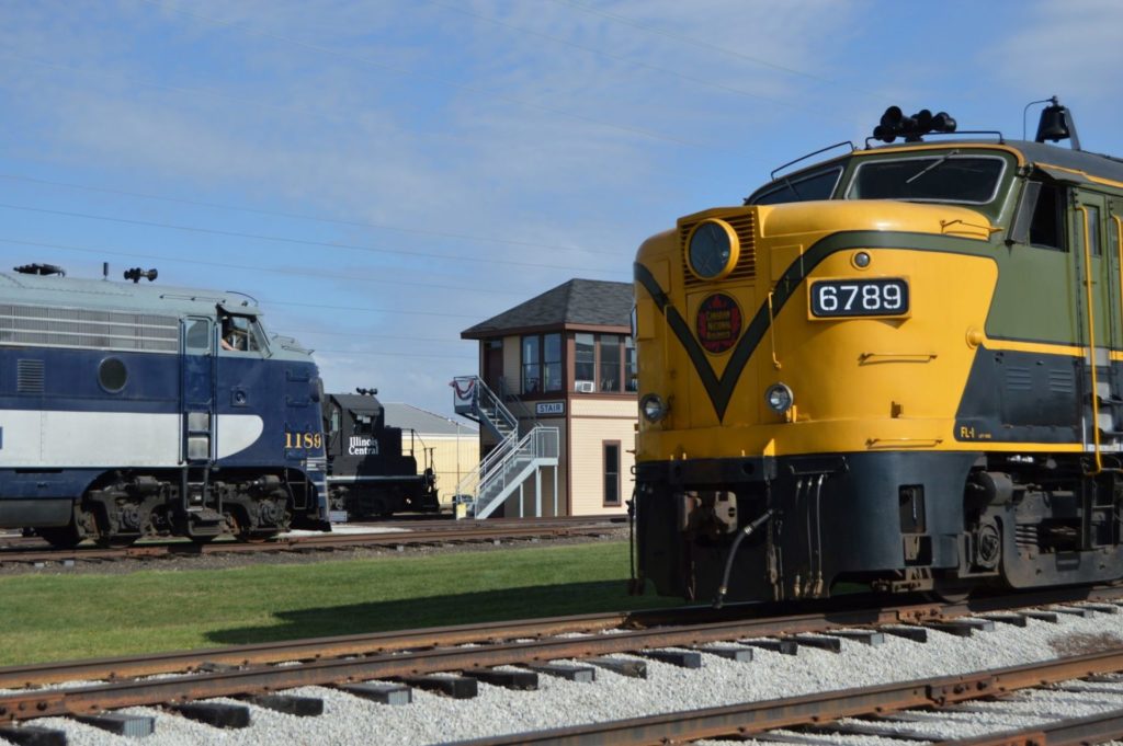 A yellow vintage train and blue vintage train facing opposite directions on parallel train tracks.