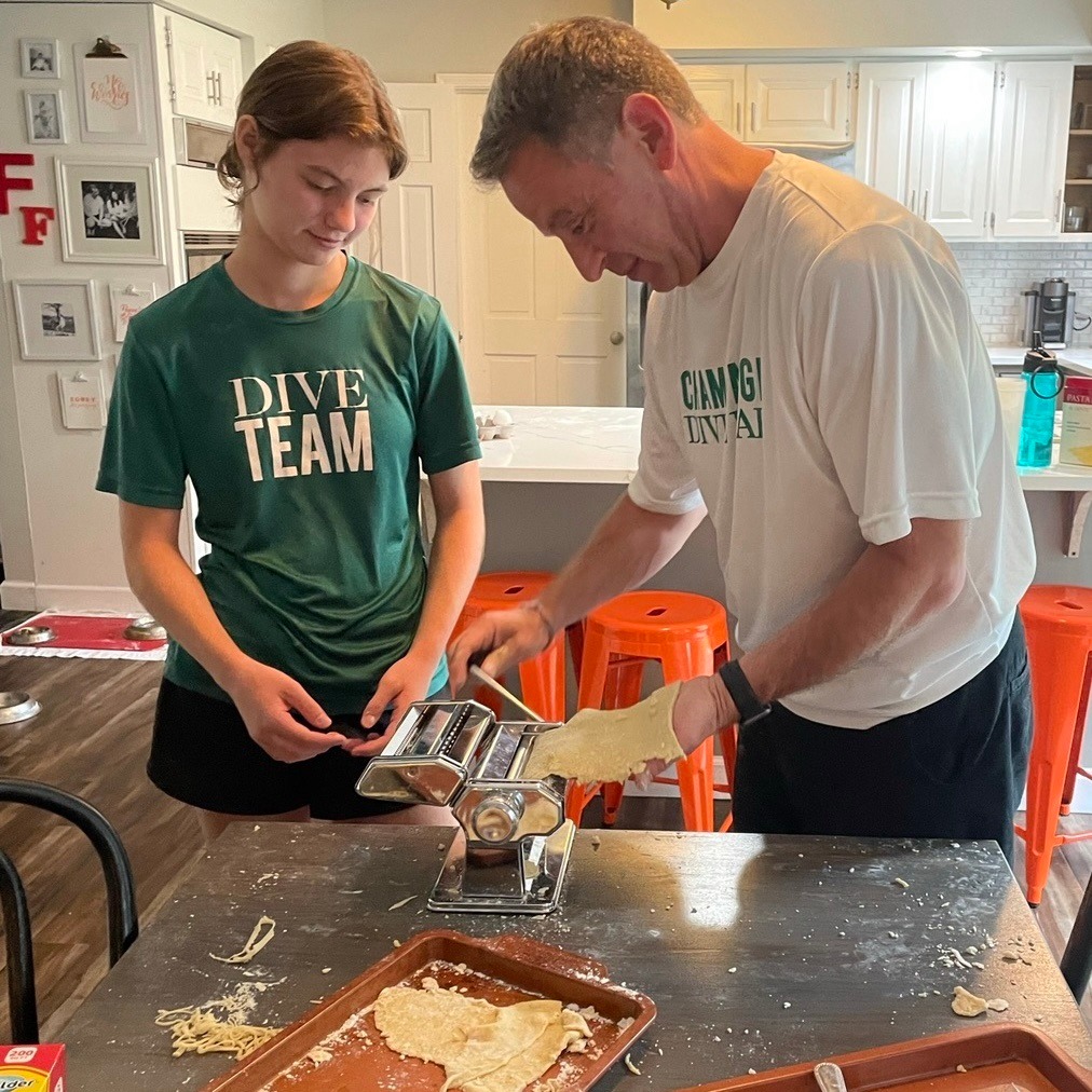 Senator Faraci and his teenage daughter are standing over a table making homemade pasta.