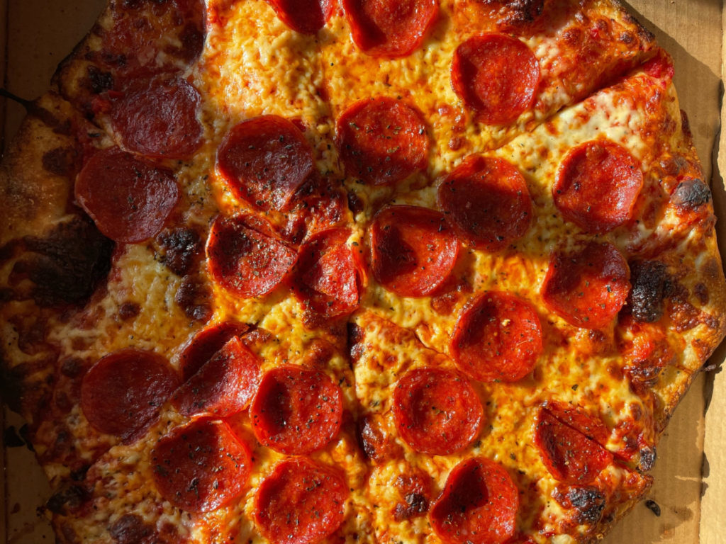 A close-up photo of a classic, triangle cut pepperoni pizza from Manolo's in Urbana.