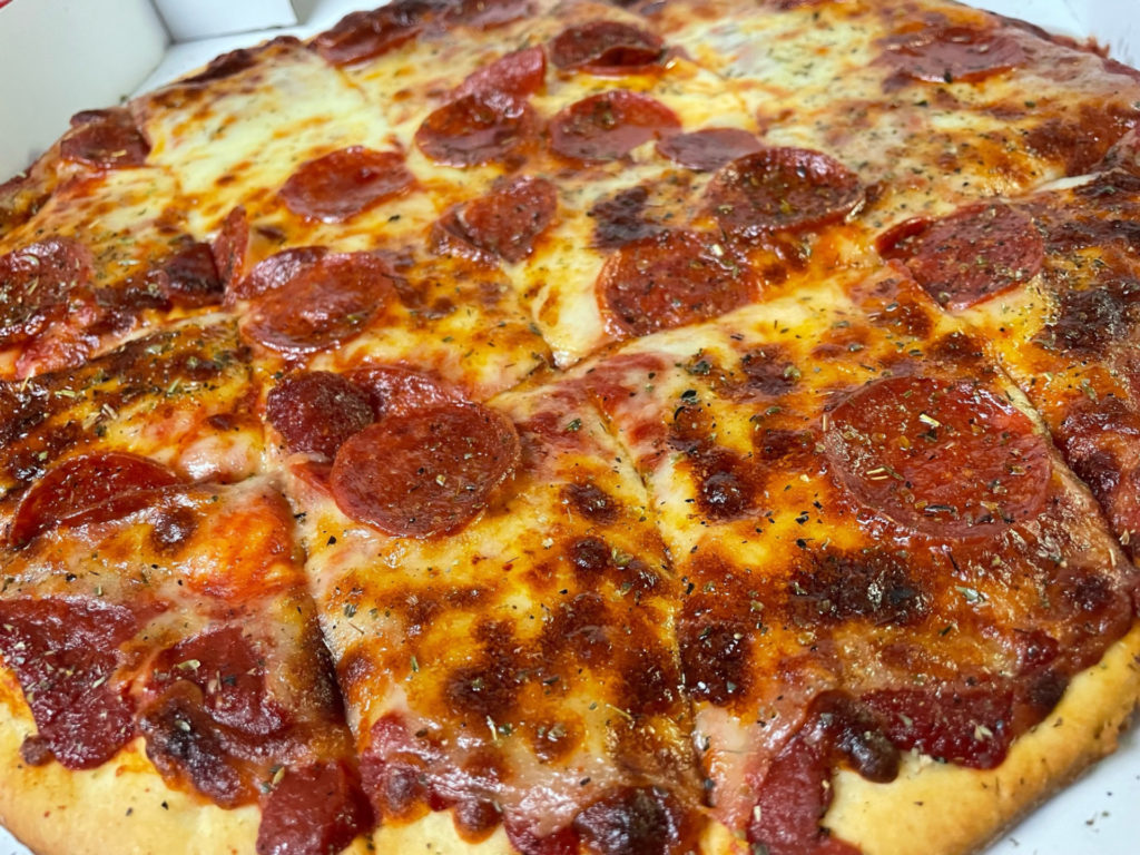 A close-up, angled photo of a square-cut pepperoni pizza.