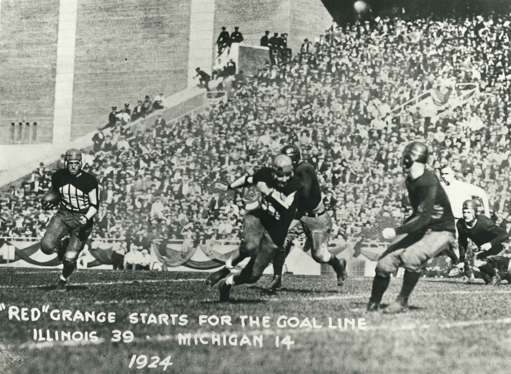 A photo of the football player Red Grange running down the field with a football.