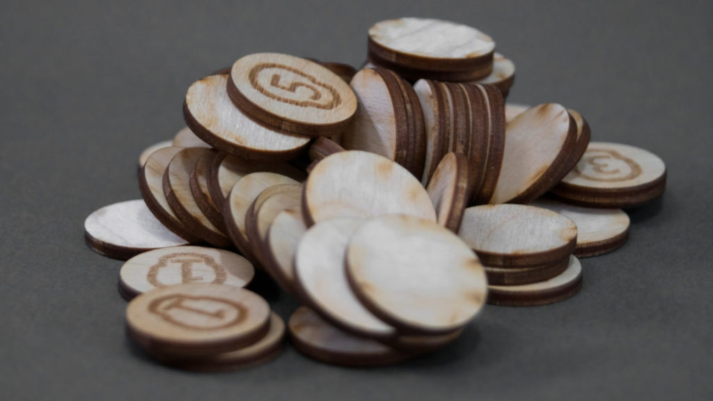 A pile of wooden game coins with different numbers on them.