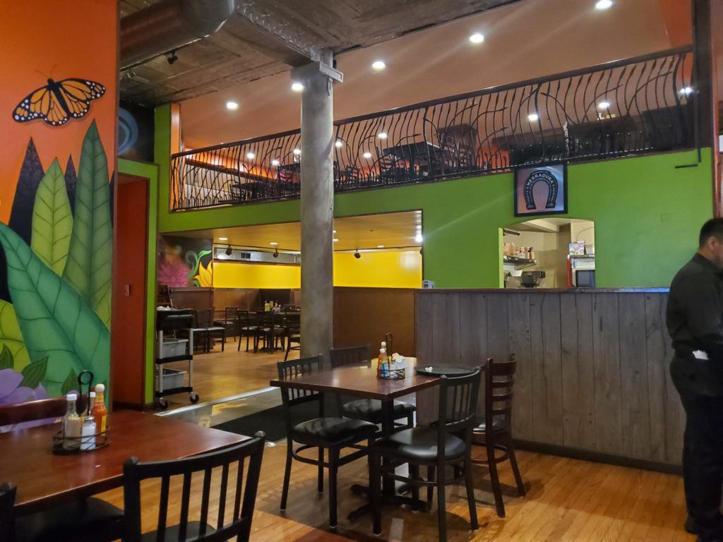 The interior of Encanto Restaurant has bright green walls with murals.