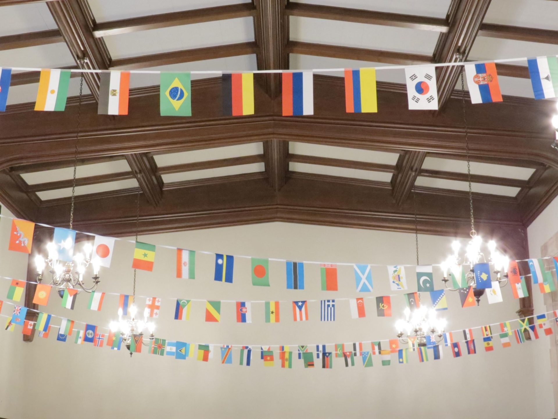 Strings of small flags from different countries stretch across the ceiling of a large room.