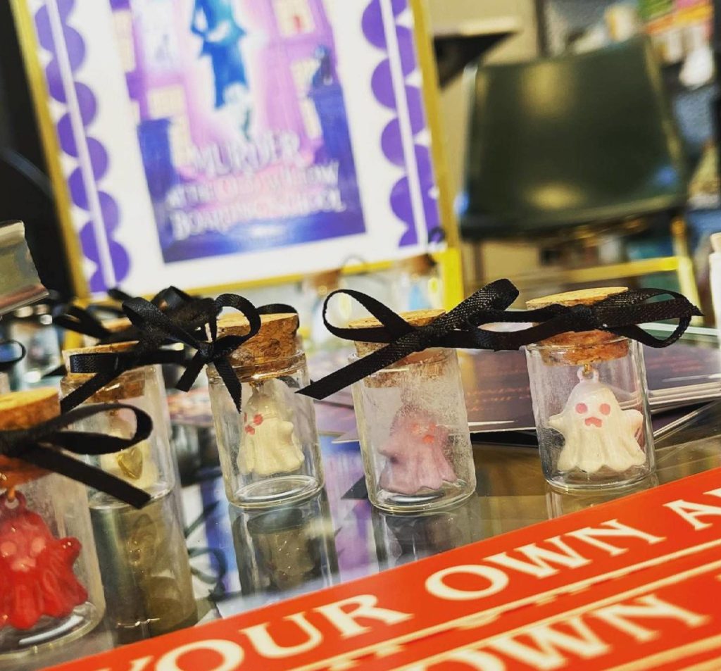 A display at the literary shows tiny clear vials with black bows and Fleck's book in the background along with a sign that says choose your own adventure.