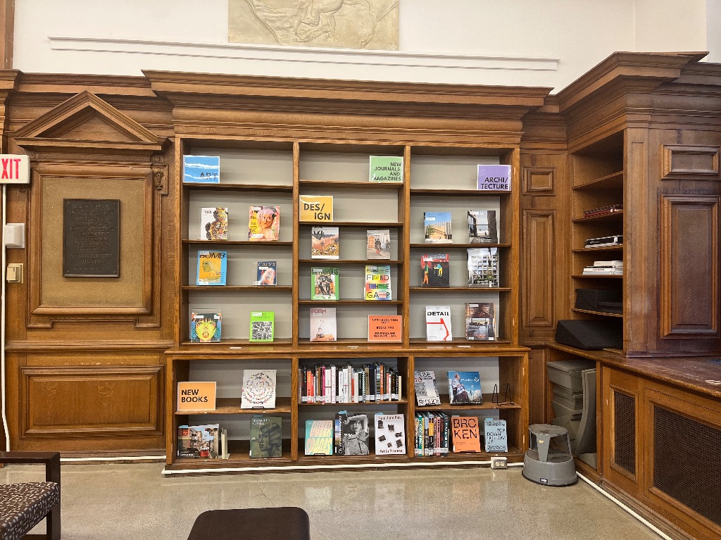 A large brown wall of shelves with colorful books and magazines. The subjects are labeled in bright colors. Art, design, architecture, and new books.