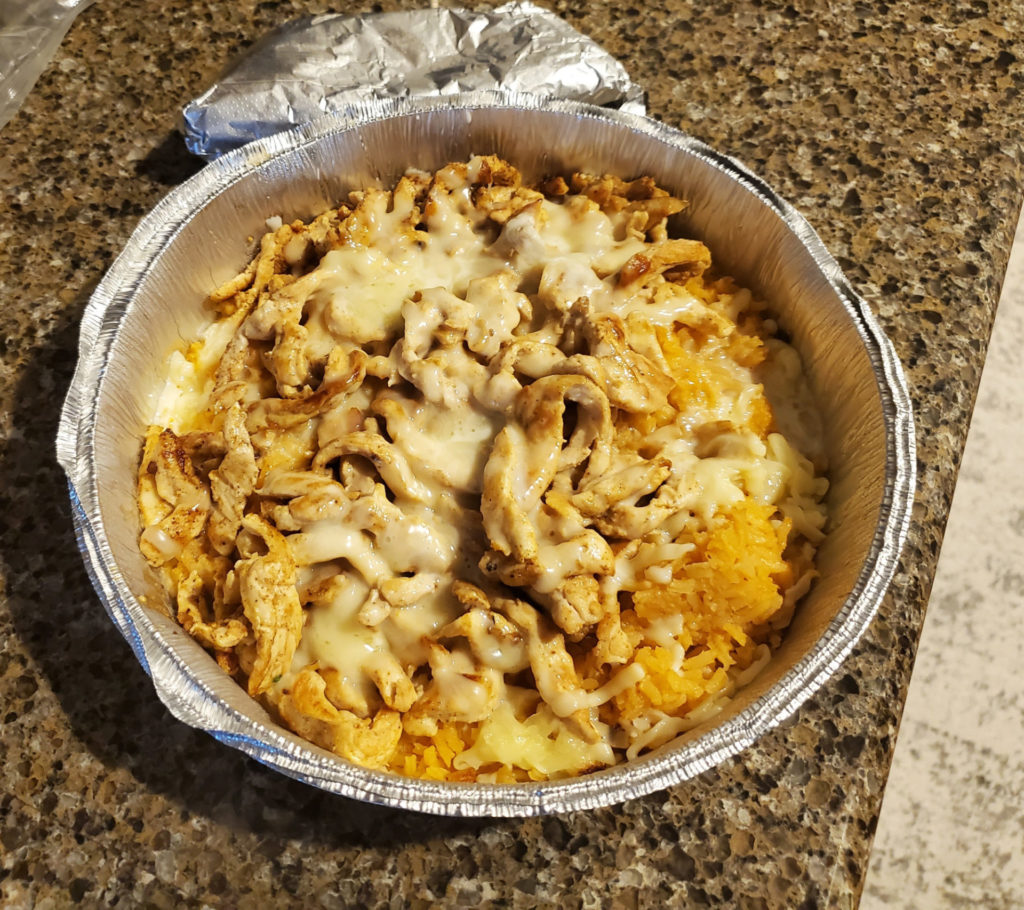 A to go container of chicken, rice, and melted cheese
