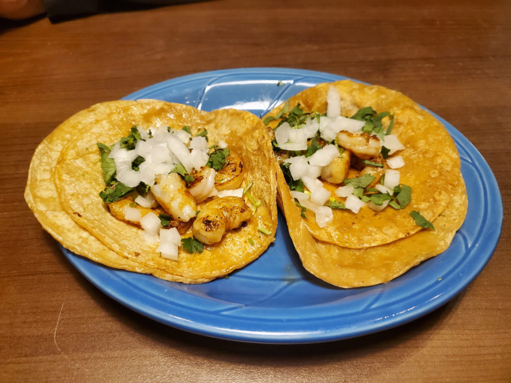 Two shrimp tacos on a blue plate.