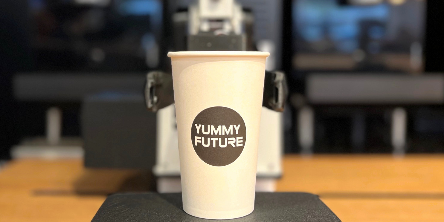 A cup with Yummy Future logo on it.