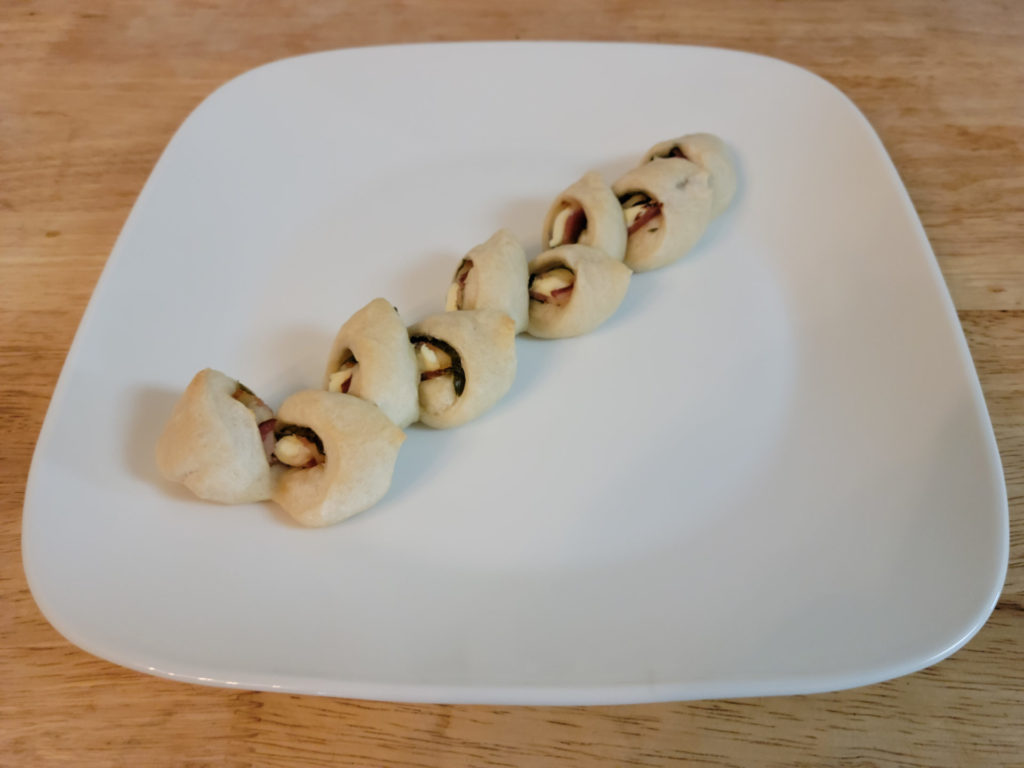A bacon shiso cream cheese bread twist with nine segments on a square plate.