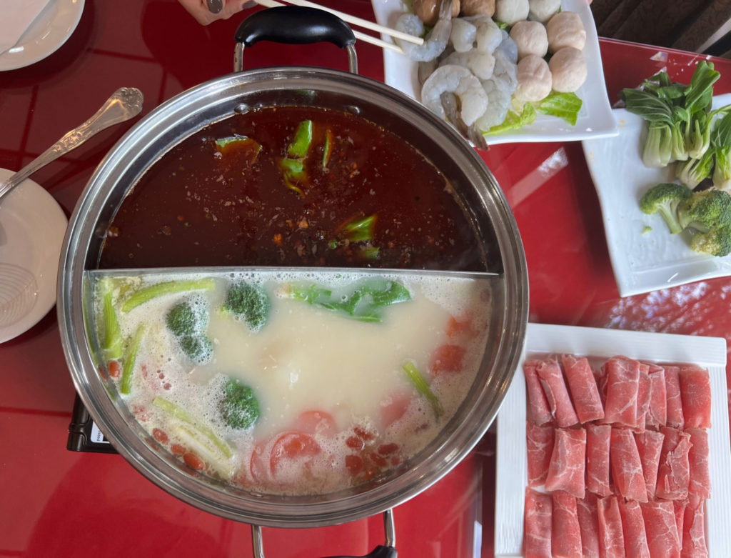 Hot pot at Chong Qing House in Champaign has two broths in a split metal pot with a side of veggies and proteins.
