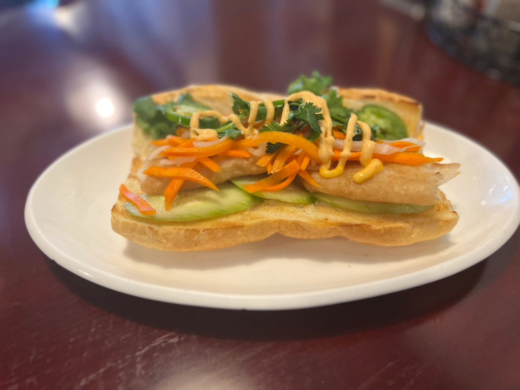 Fish banh mi on a white oval plate.