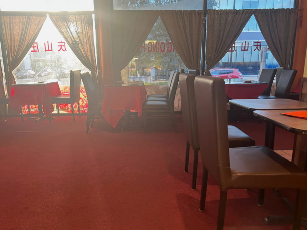The interior of Chong Qing has a red carpet with burgundy chairs and red tablecloths.