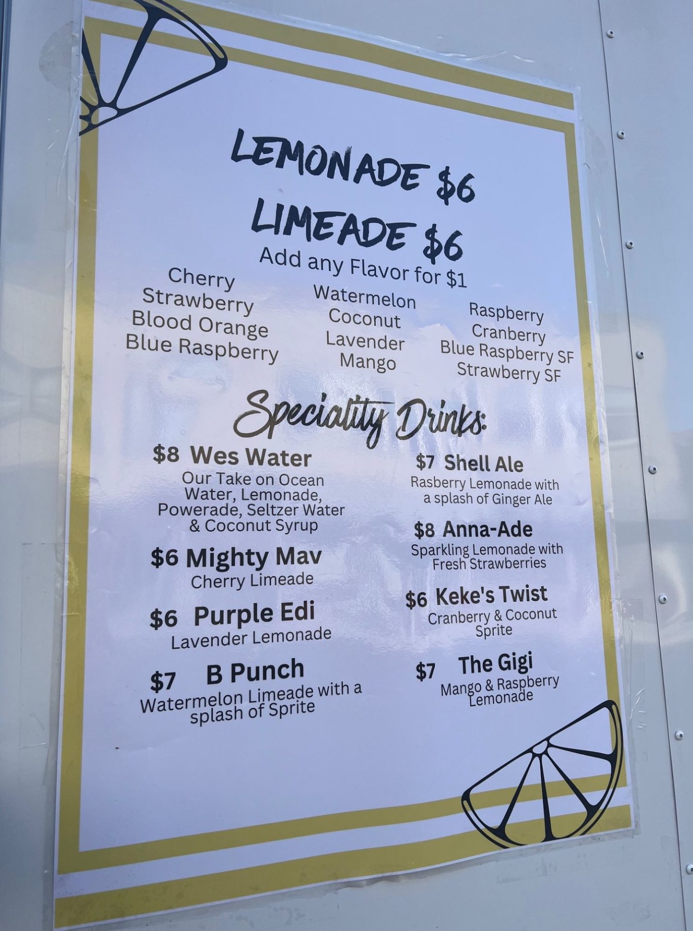 Menu poster taped to the side of a white truck, featuring Lemonade, Limeade, and a variety of drink options. 