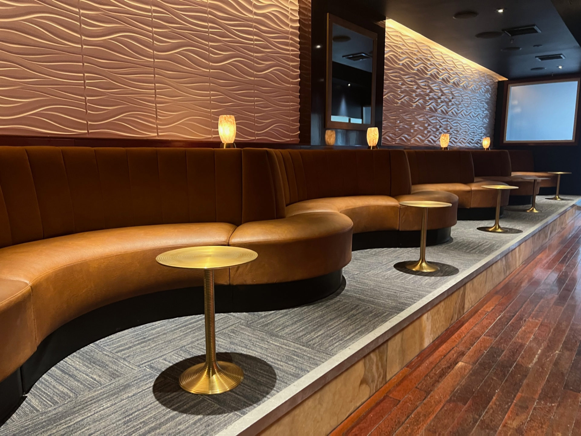 The interior of Anthem bar in Downtown Champaign has brown leatherettes with gold side tables.