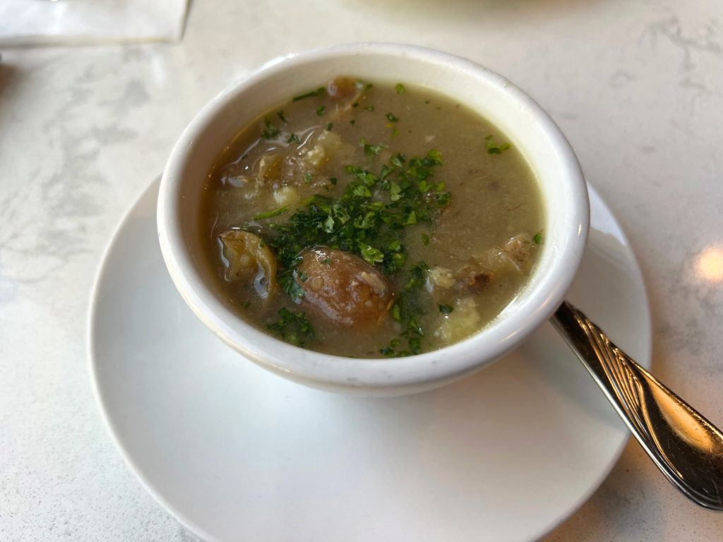 A cup of soup with pieces of red potato and chopped parsley on a marble bar at Hamilton Walker's in Champaign, Illinois.
