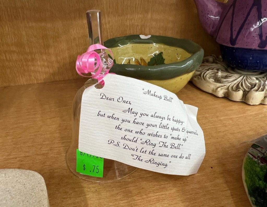 A small glass bell with a note attached, indicating that it's a "Make Up Bell", and a person wishing to make amends should ring it.