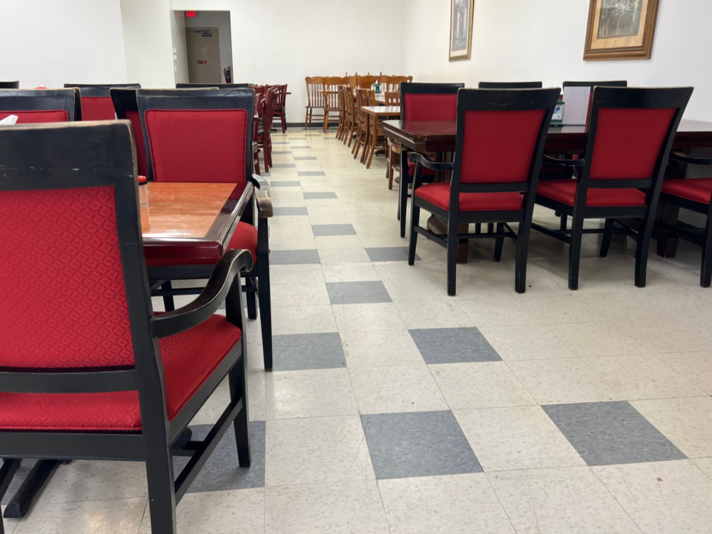 The interior or Sepelas restaurant has red chairs with brown tables.