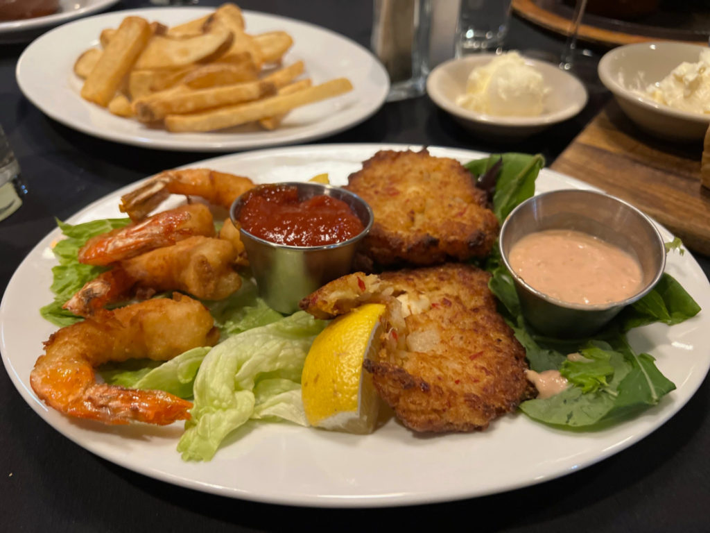 A seafood plate with four shrimp and two crab cakes.