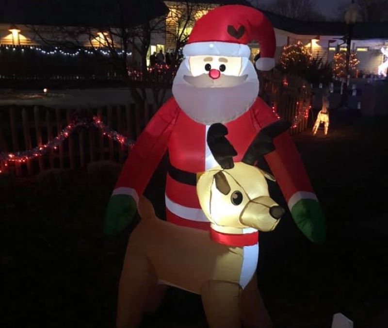 An inflatable Santa and reindeer decoration, lit up at night.