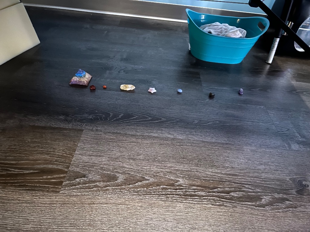 A wood floor with a line of crystals in various colors and shapes. 