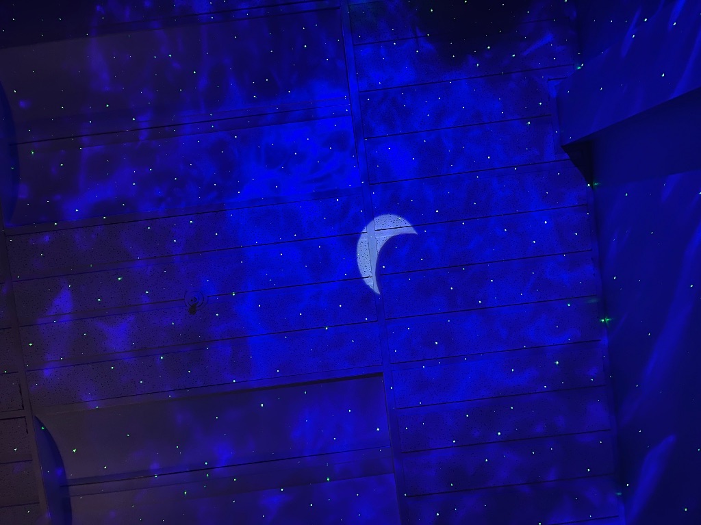 A projected image of a moon and stars on the ceiling. 
