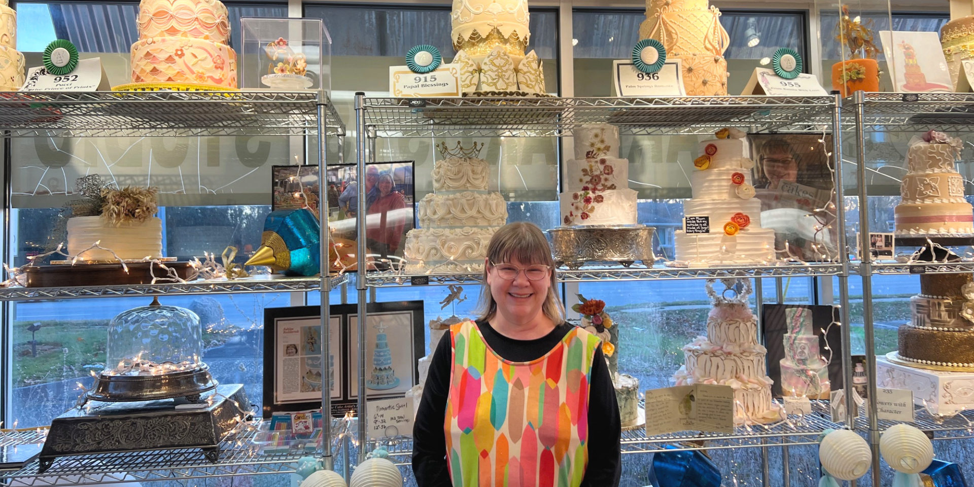 Ashlee Freeburg, The Cake Artist of The Cake Artist's Studio in Champaign, stands in front of many of her beautifully decorated cakes.