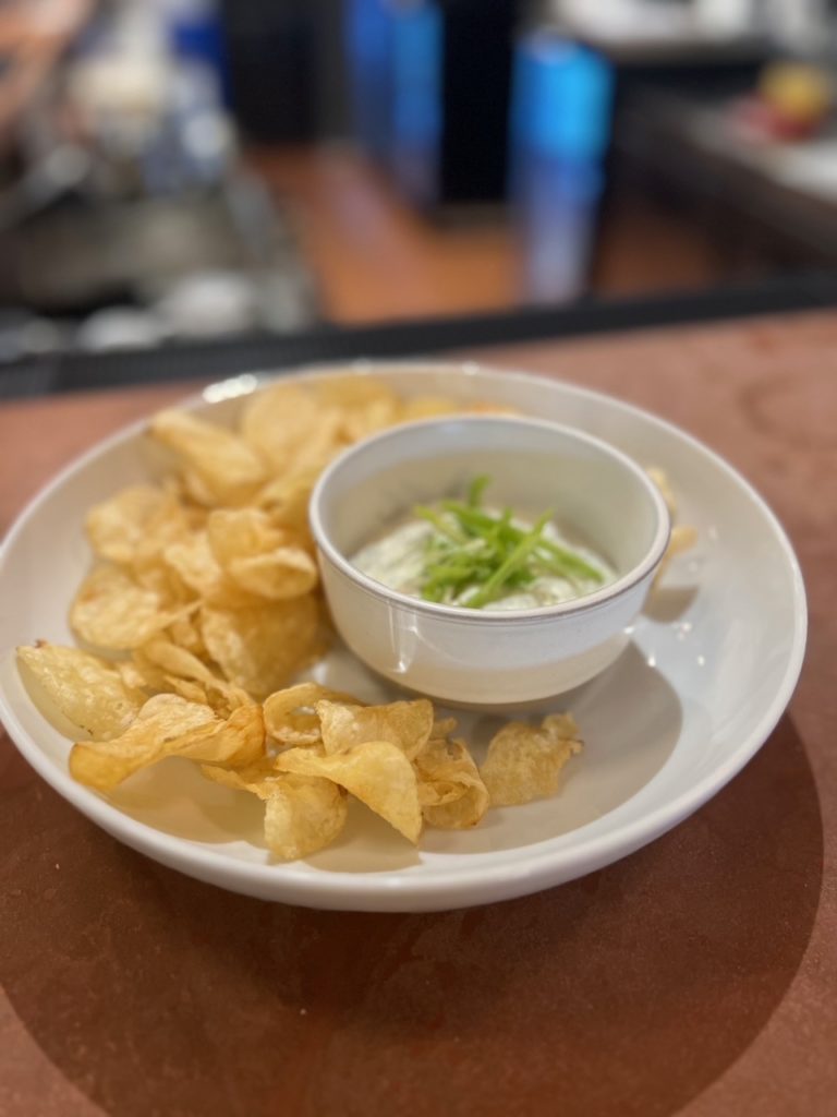 A plate of kettle chips with a dill dip.