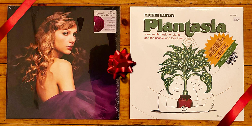 The image displays two vinyl record covers. The cover on the left shows a close-up of a person’s shoulder and hair, with the person wearing a purple dress. The cover on the right features a cartoon of two people hugging a plant. The people are naked and their bodies form the shape of a heart. The plant is in a pot and has large leaves. The text on the right cover reads “Mother Earth’s Plantasia - warm earth music for plants…and the people who love them”. There is a red satin ribbon and a bow on top.