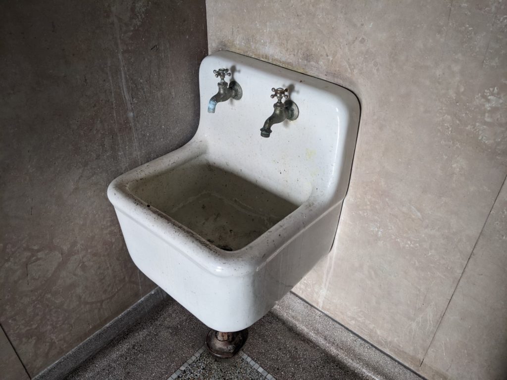 An old small white sink with small taps that turn on from the top. 