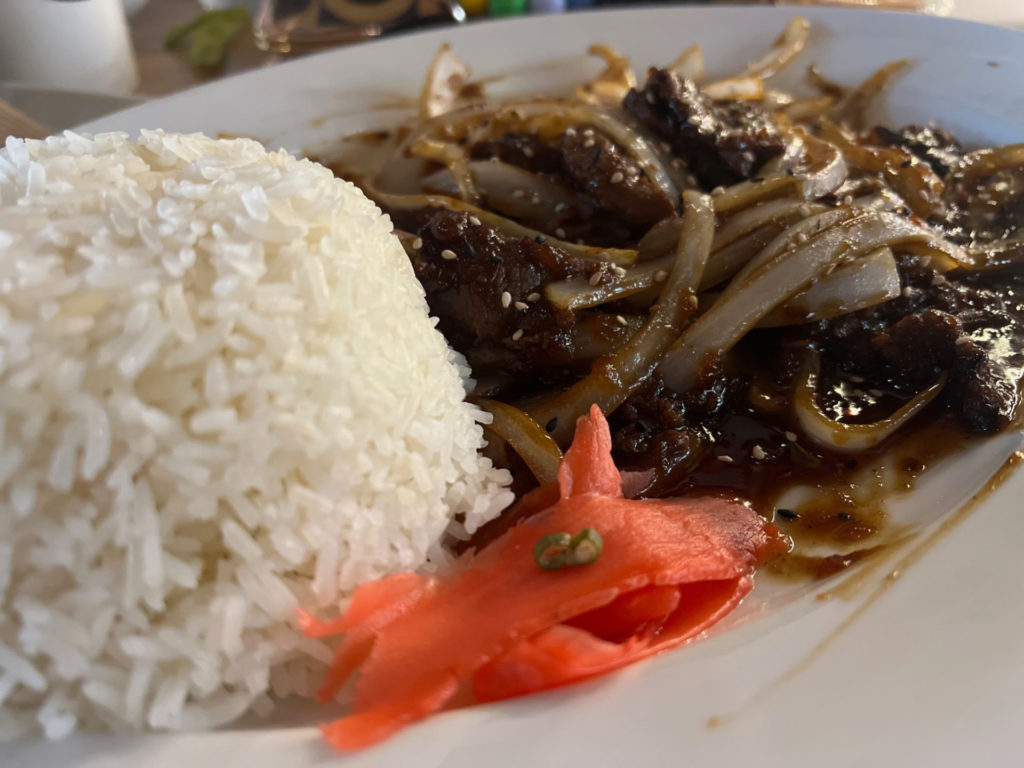 Beef bulgogi on a white plate with white rice.
