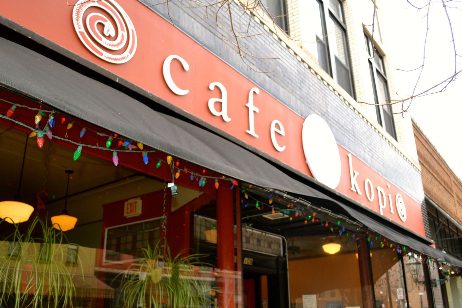 The front of Cafe Kopi, focused on the red sign with white letters.