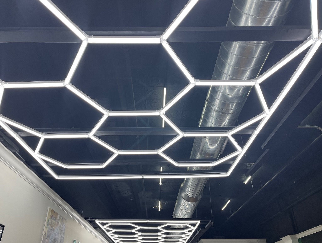 Inside of groom culture, a black painted celiing with honeycomb neon lights. 