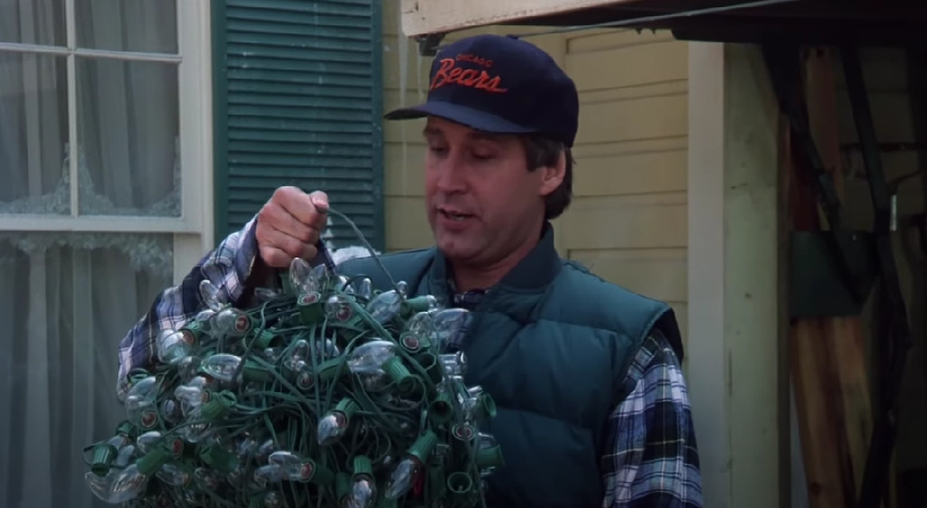 Clark Griswold from National Lampoon's Christmas Vacation, holding a tangled ball of holiday lights.