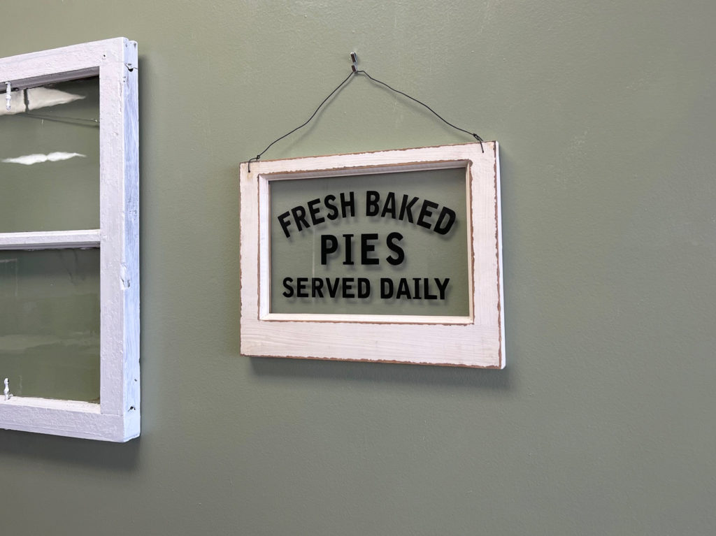 A framed glass has blank inked words "Fresh Baked Pies Served Daily" inside the new Lucky Moon Bakery.