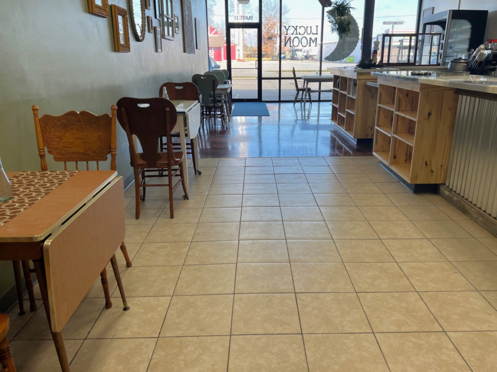 The interior of Lucky Moon Pies & more has chairs and tables long the left side and a counter with café items on the right.