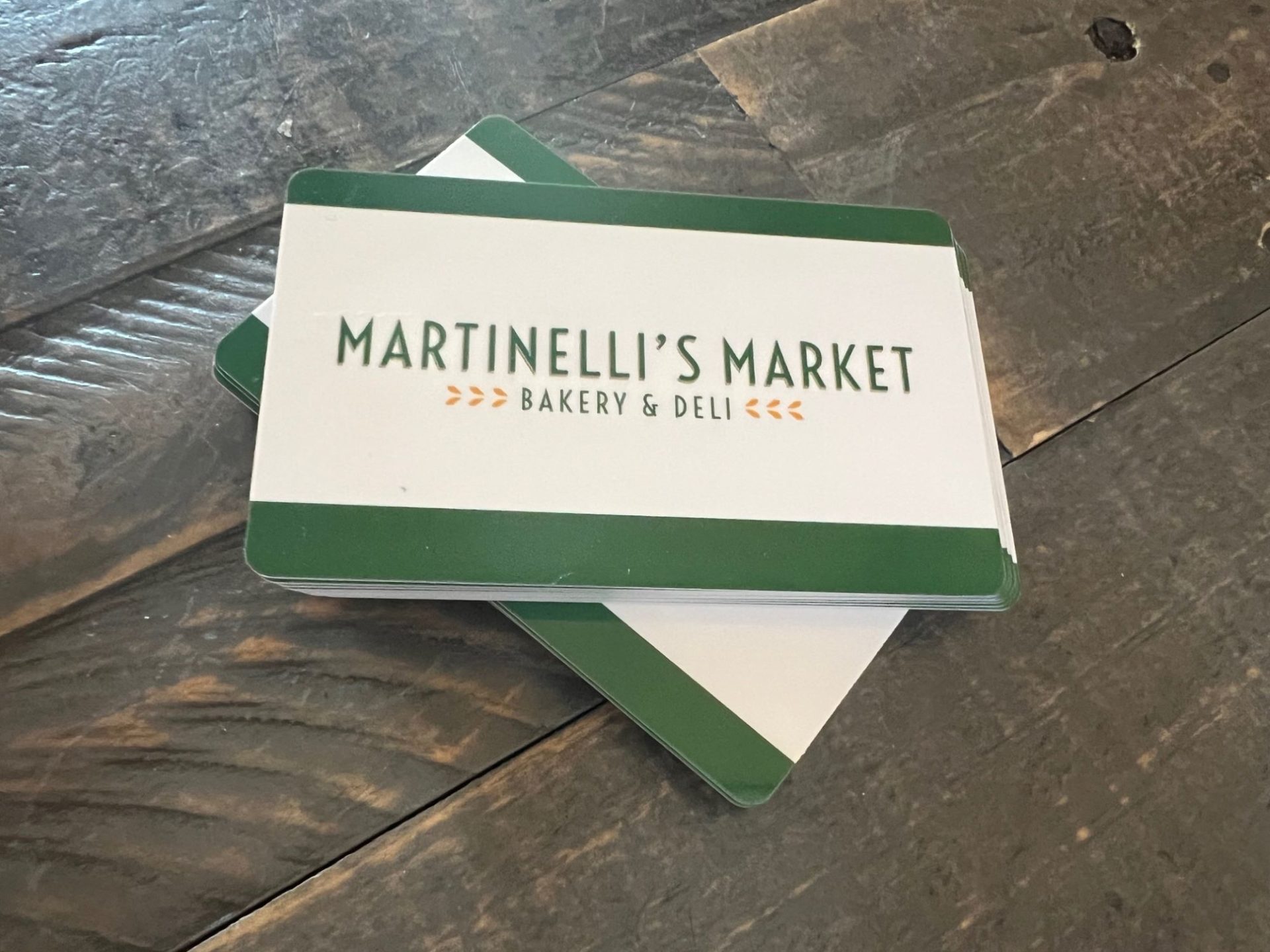 Two stacks of green and white gift cards that say Martinelli's Market, sitting on a gray table.