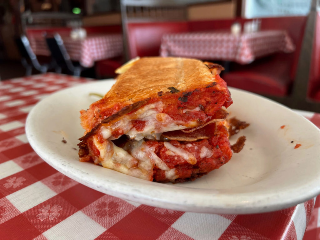 A pizza sandwich foled in half with lots of red tomato sauce.