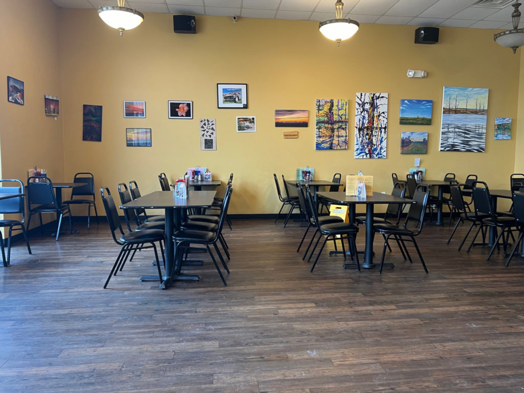 Po' Boys dining room in Urbana is empty, but black chairs are neatly pushed into black tables in a bright room.